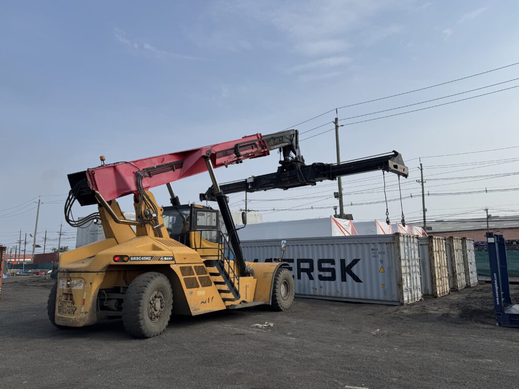Reach stacker working beside stacked Maersk containers